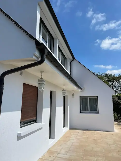 Façade de pavillon repeinte en blanc, gouttières anthracite conservées — résultat après ravalement Diamond Peinture en Île-de-France